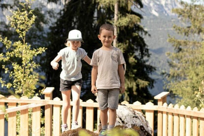 2 Kinder balancieren über einen Baumstamm