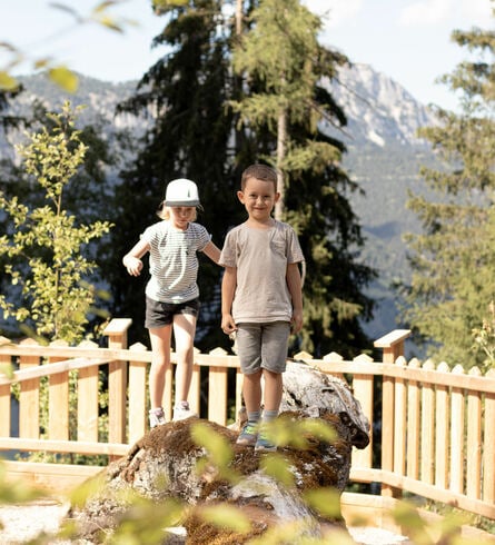 2 Kinder balancieren über einen Baumstamm