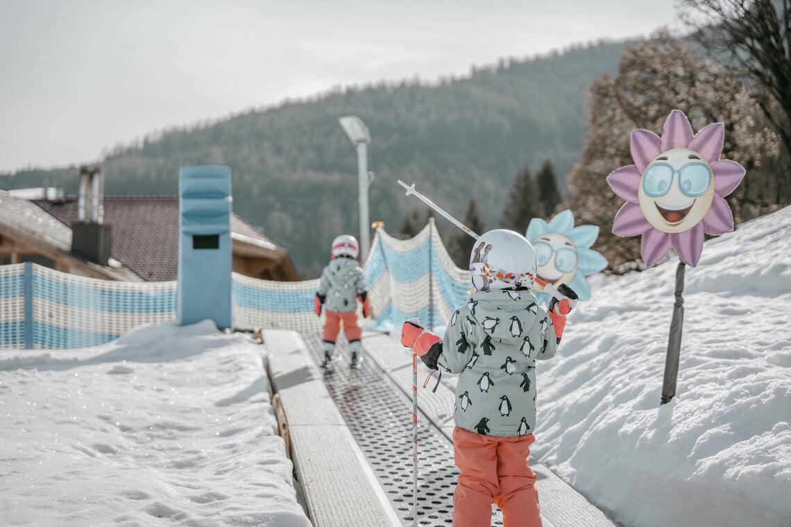 2 Kinder fahren den Teppichlift hoch