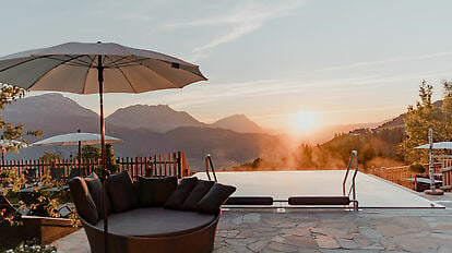 Pool im Vordergrund bei Sonnenaufgang und Blick auf das Ennstal und die Bergew.