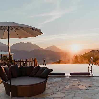 Pool im Vordergrund bei Sonnenaufgang und Blick auf das Ennstal und die Bergew.