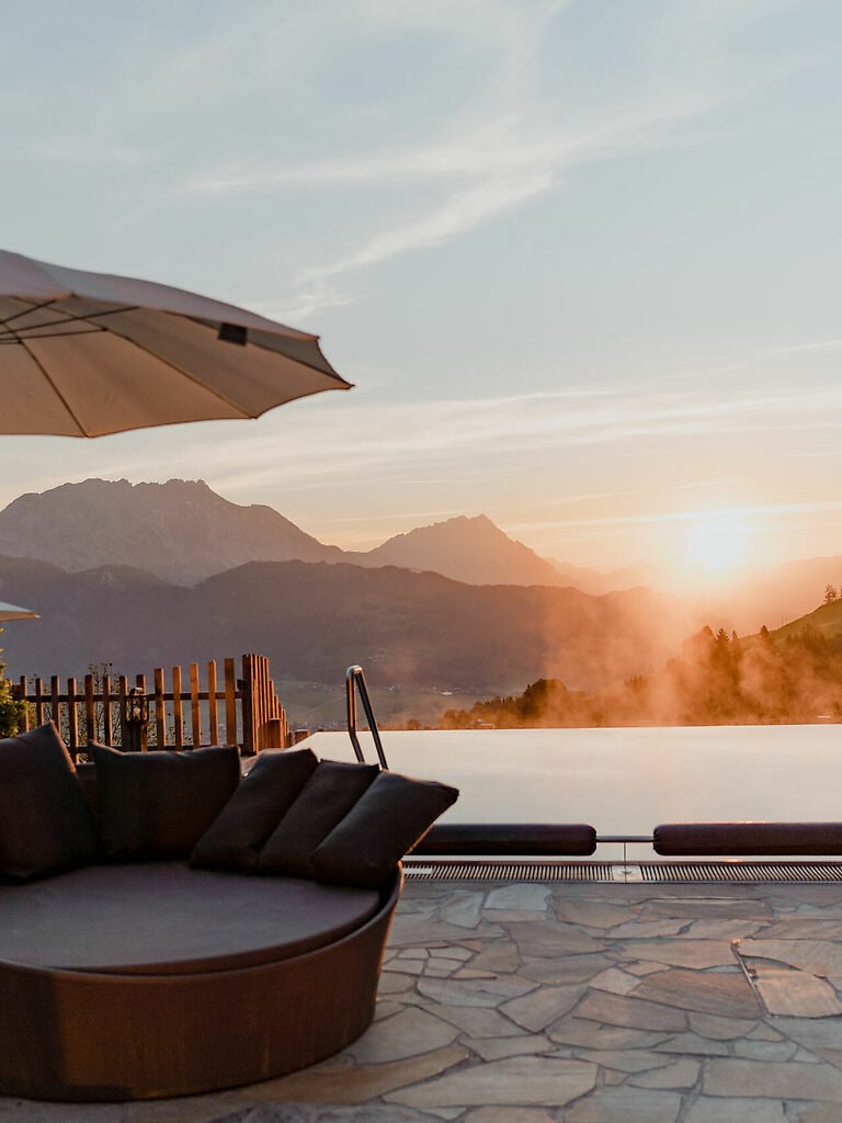 Pool im Vordergrund bei Sonnenaufgang und Blick auf das Ennstal und die Bergew.